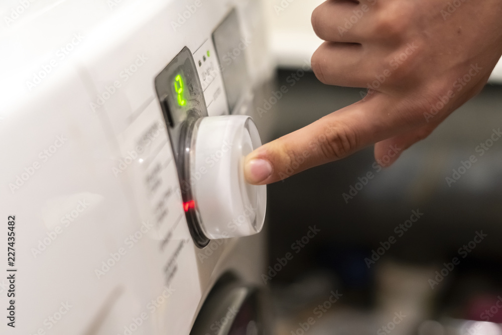 close up hand pushing the button to start the washing machine f close up hand pushing the button to start the washing machine f