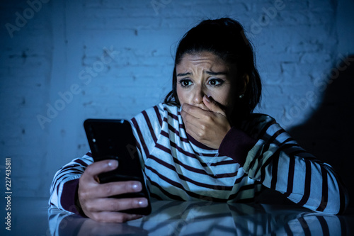 Worried unhappy young woman suffering from cyberbullying and harassment online by mobile phone photo