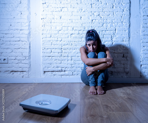 Bild auf Leinwand Sad woman or teenager girl afraid of weight looking at scale in eating disorder