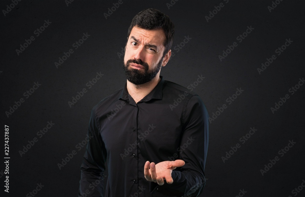 Tired handsome man with beard on black background
