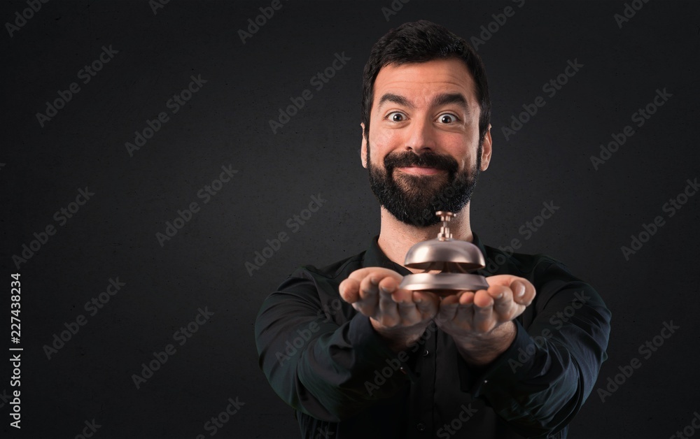 Handsome man with beard with ringbell on black background