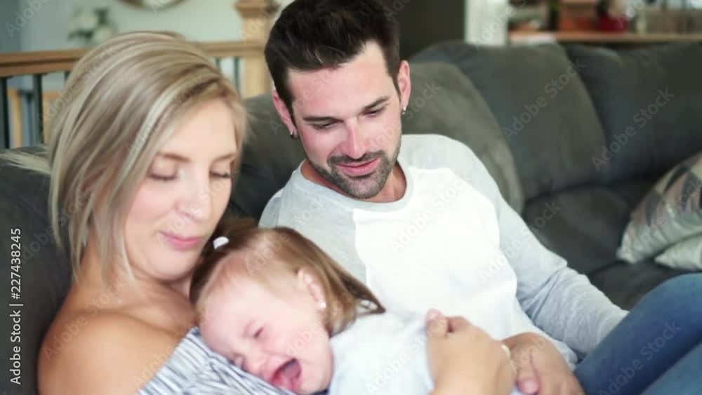 Young family with baby daughter on sofa at home, the baby crying Young family with baby daughter on sofa at home, the baby crying