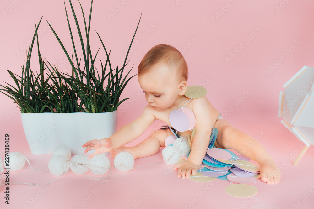 Baby. Newborn in the diaper. Isolated. Toddler playing with toy. Pink background