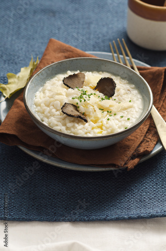 Risotto with black truffle and parmesan cheese in blue plate on rustic linen tablecloth, Copyspace.