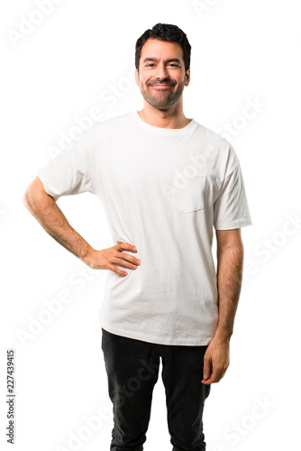 Young man with white shirt posing with arms at hip and smiling on isolated white background