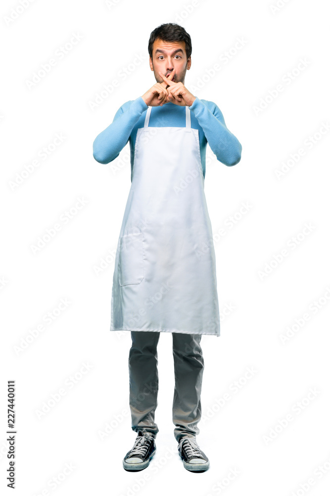 A full-length shot of a Man wearing an apron showing a sign of closing mouth and silence gesture on isolated background A full-length shot of a Man wearing an apron showing a sign of closing mouth and silence gesture on isolated background