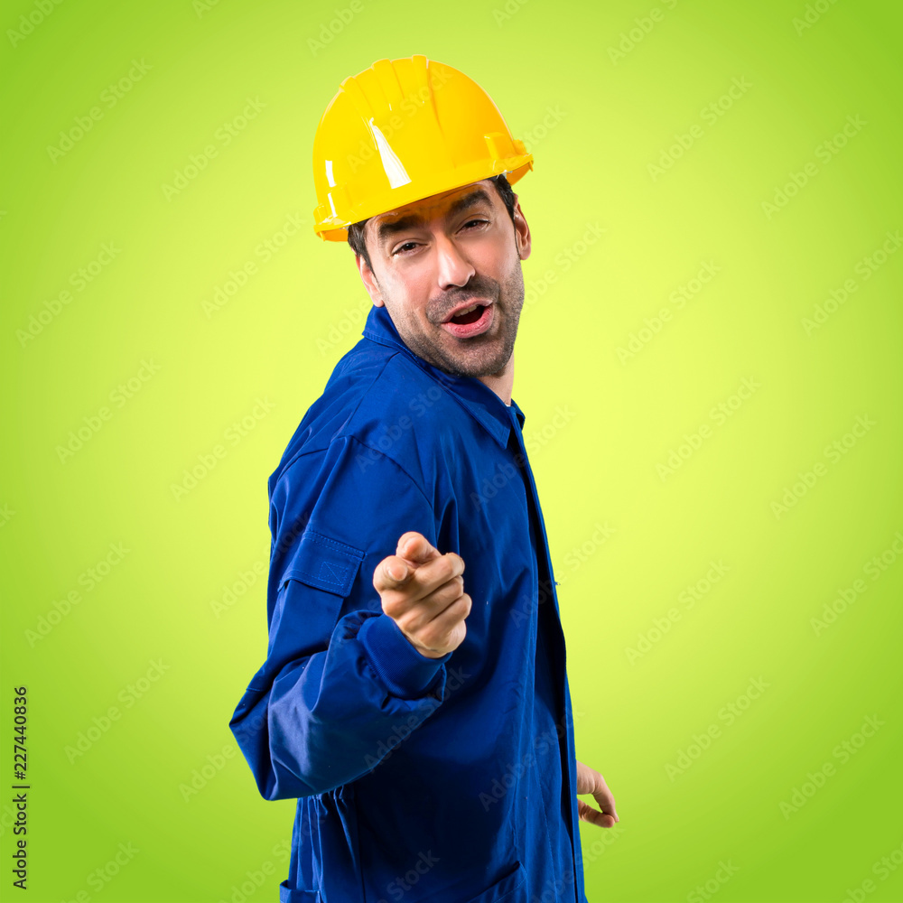 Young workman with helmet enjoy dancing while listening to music at a party on green background