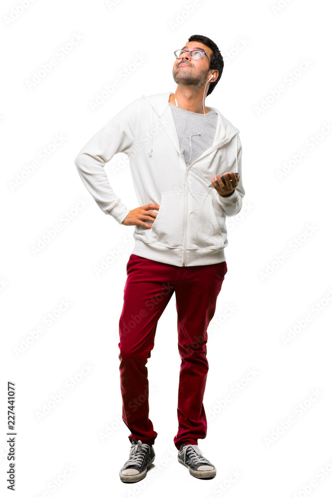 A full-length shot of a Man with glasses and listening music stand and looking up on white background A full-length shot of a Man with glasses and listening music stand and looking up on white background