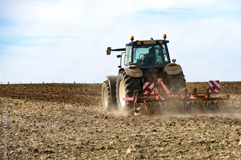 Fototapeta premium tracteur agricole avec le déchaumeur en action sur le champ