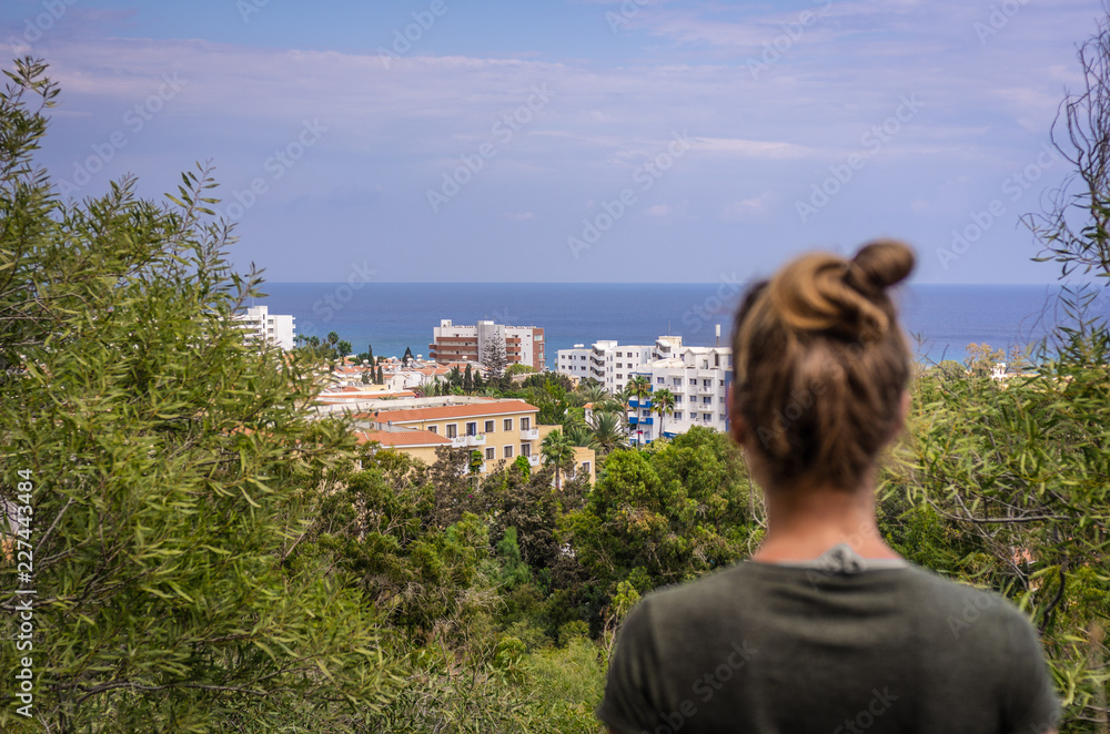 A woman stares into the distance to the sea horizon and the city in front of him A woman stares into the distance to the sea horizon and the city in front of him