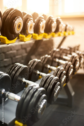 dumbbells row in a gym. sport sunny background photo