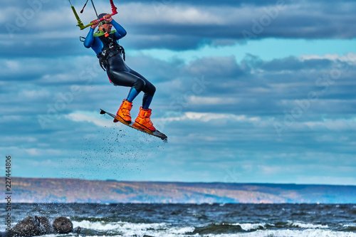 A male kiter jumps over a large lake. Close-up.