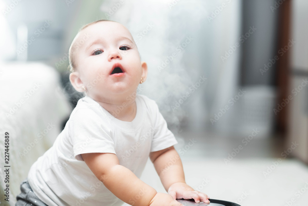 Little baby looks at the humidifier. Moisture in the house concept Little baby looks at the humidifier. Moisture in the house concept