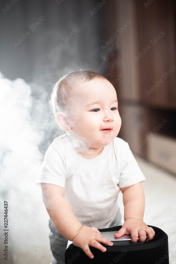 Little baby looks at the humidifier. Moisture in the house concept Little baby looks at the humidifier. Moisture in the house concept