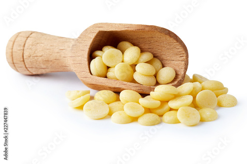 Organic cacao butter buttons (wafers) in wooden scoop isolated on white background