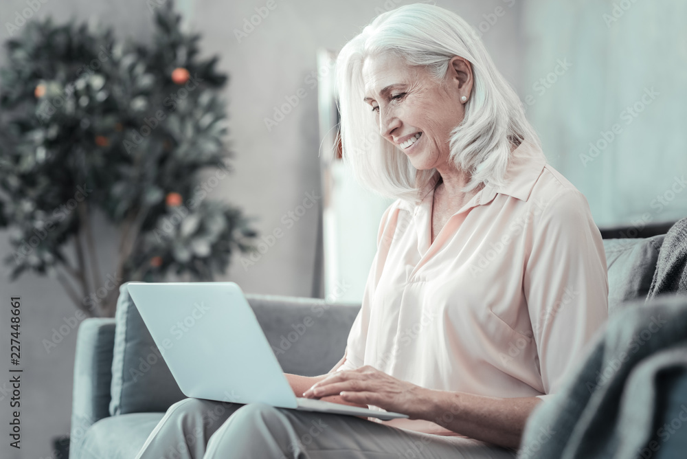 Internet connection. Joyful nice aged woman holding her netbook and looking at its screen while surfing the Internet Internet connection. Joyful nice aged woman holding her netbook and looking at its screen while surfing the Internet