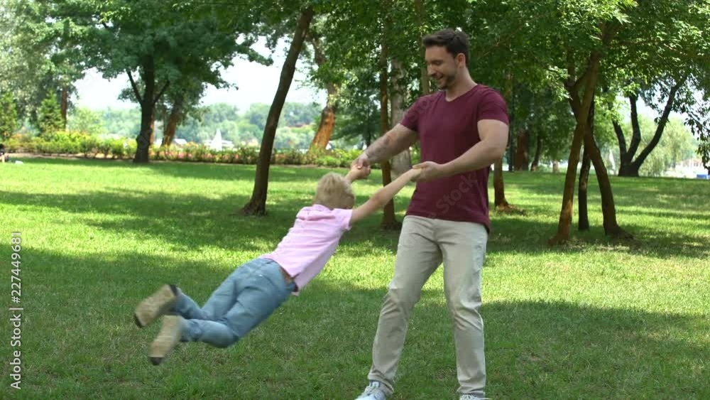 Dad and son playing in park, showing thumbs up, appreciate time with family Dad and son playing in park, showing thumbs up, appreciate time with family