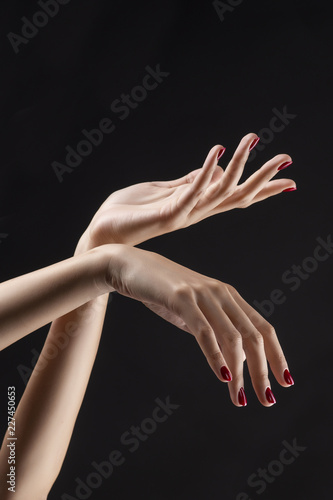 Closeup of beautiful woman hands with red manicure on the nails. Cream for palms, manicure and beauty treatment. Elegant and graceful arms with slender graceful fingers.