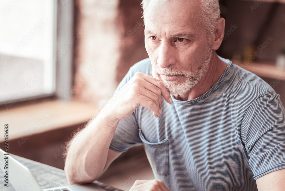 Contemplations. Close up of elderly man being thoughtful while looking away and keeping his hand under his chin Contemplations. Close up of elderly man being thoughtful while looking away and keeping his hand under his chin