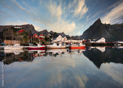 Rising sun lights up the harbor and boats in the town of Moskenes. Reine, Lofoten, Norway. photo