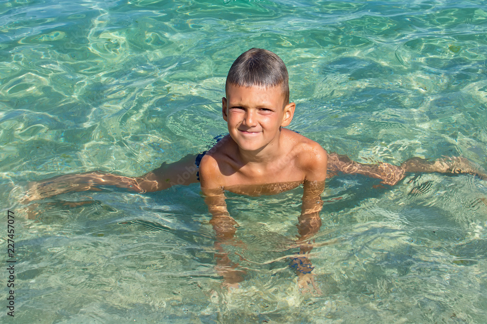 the boy poses in the water at sea