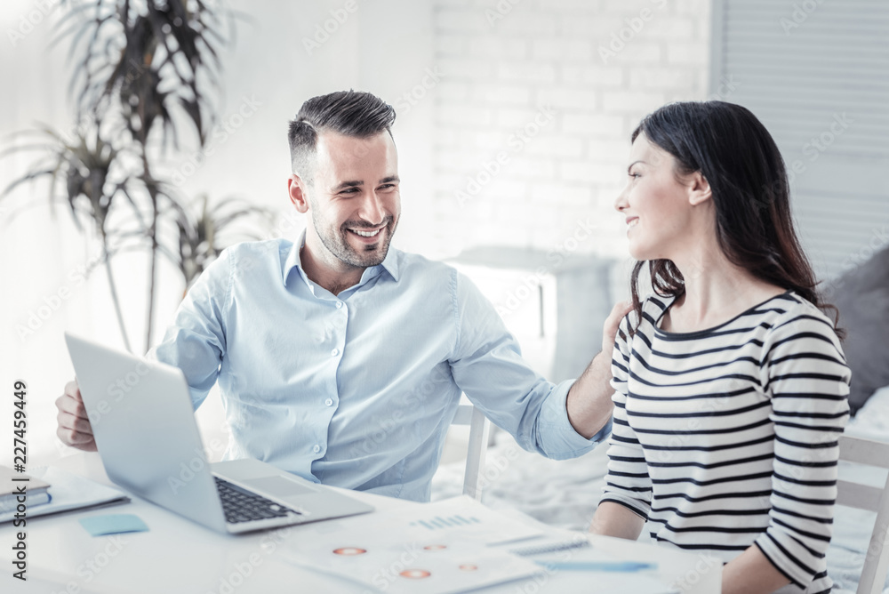 Fototapeta premium Partner work. Delighted female keeping smile on her face and turning head while looking at her friend