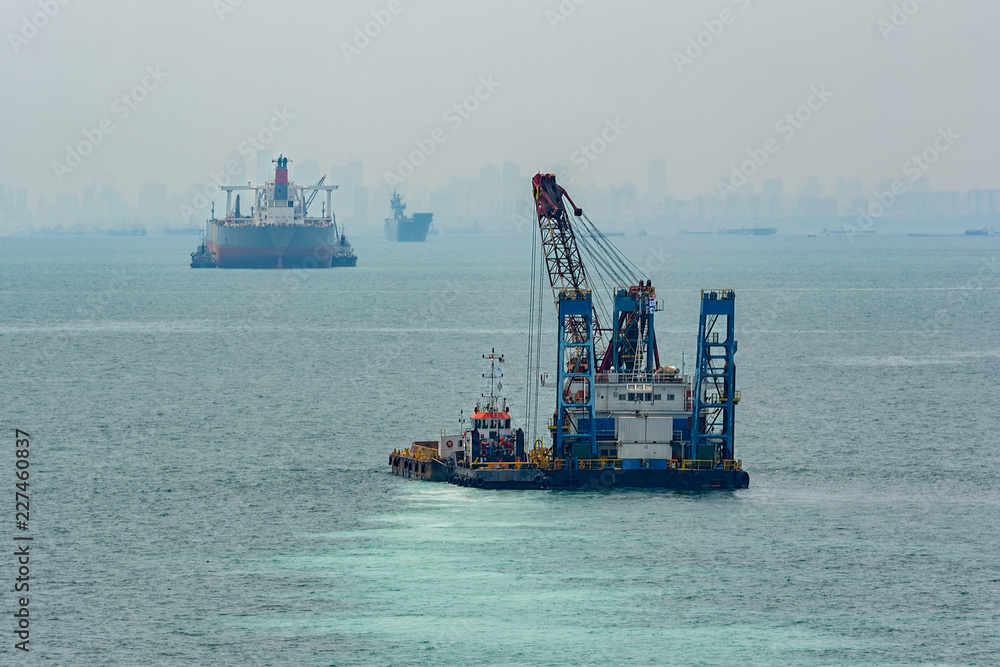 Grab Dredger - revolving crane, fitted with a grab, placed on a hopper vessel or pontoon. Singapore Strait.