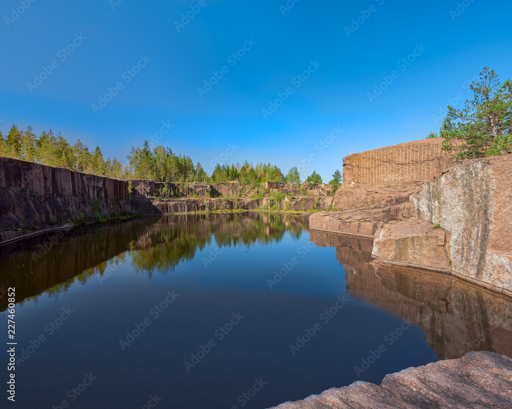 Blue pond formed at the bottom of the abandoned granite quarry.