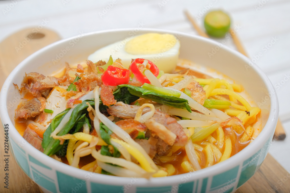 Mee Rebus in the bowl  with chopsticks on white table This dish is made of noodles ,vegetable,egg with a spicy .