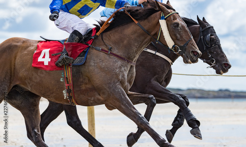 Close-up on two race horses and jockeys competing in a race