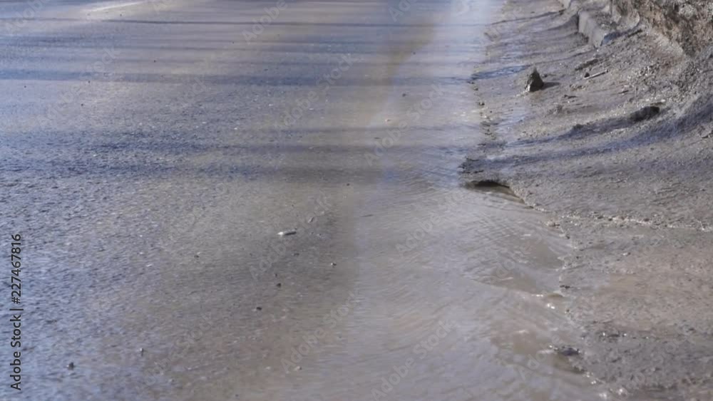 Spring stream flowing through the asphalt. Melting snow in spring. Looping . Spring stream flowing through the asphalt. Melting snow in spring. Looping .