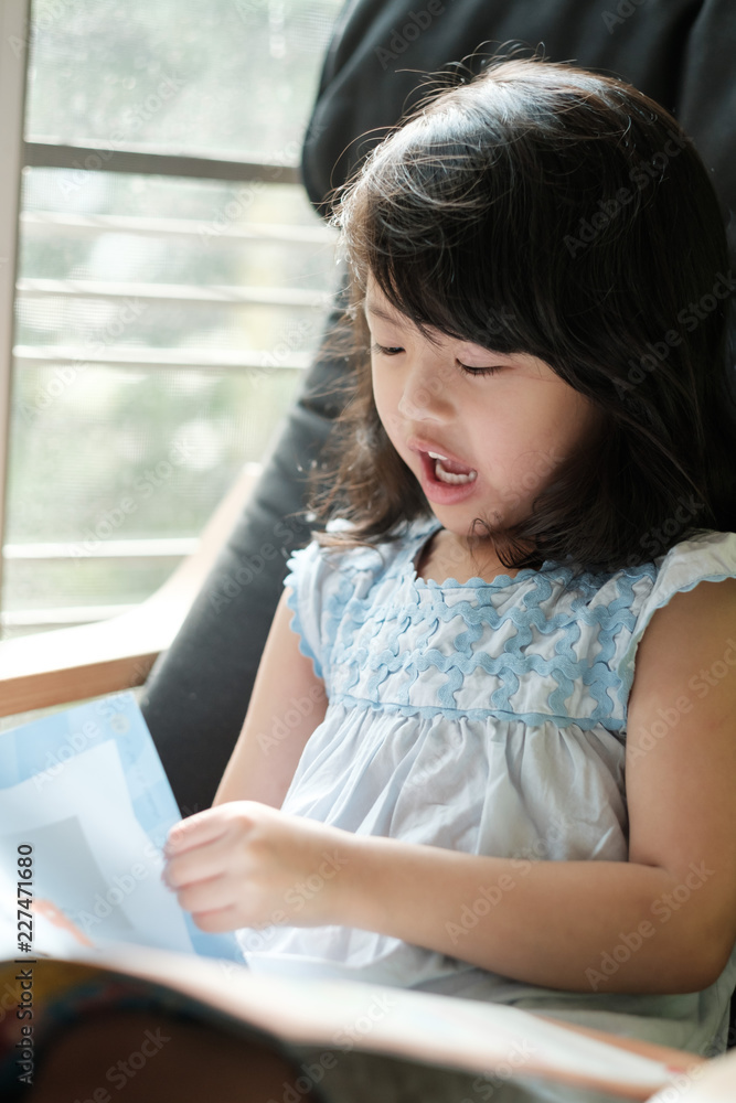 Children sitting reading books by the window Children sitting reading books by the window