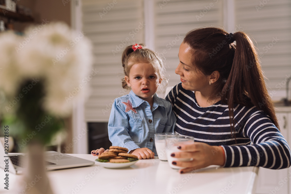 Mother and daughter eating cookies and milk