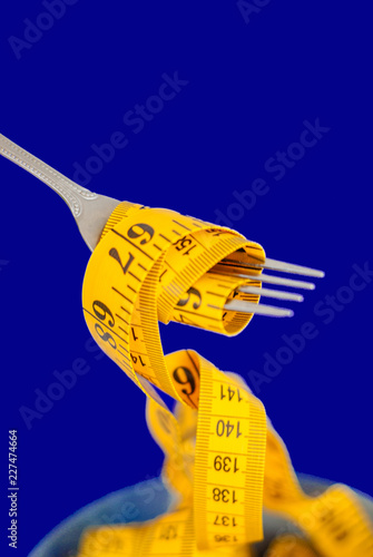 The concept of the diet. The fork rewound centimeter lying on plate closeup