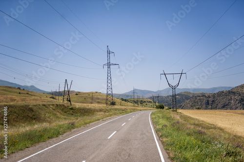 Winding road with electricity wires along the edge running through a mountainous landscape