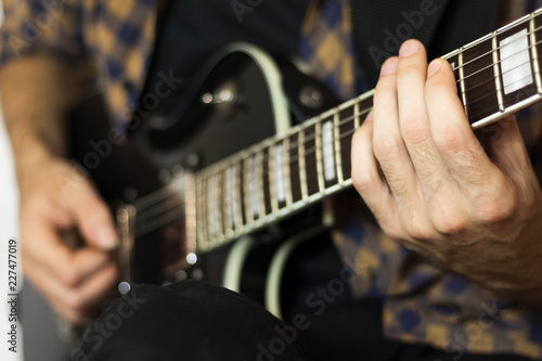 Young man playing on electric guitar