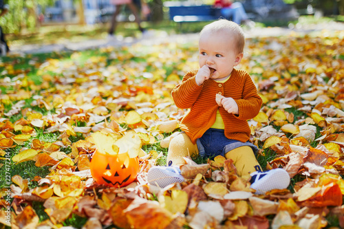 Cute little baby girl having fun on beautiful fall day