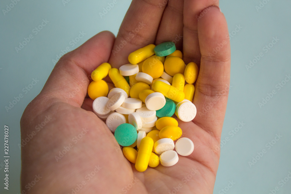 a lot of colorful pills in a woman's palm on ight background, medication concept a lot of colorful pills in a woman's palm on ight background, medication concept