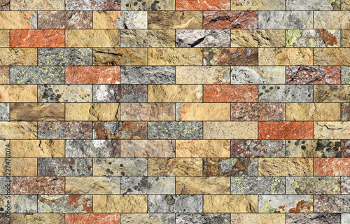 Fragment of a decorative stone wall with lichen on the surface.