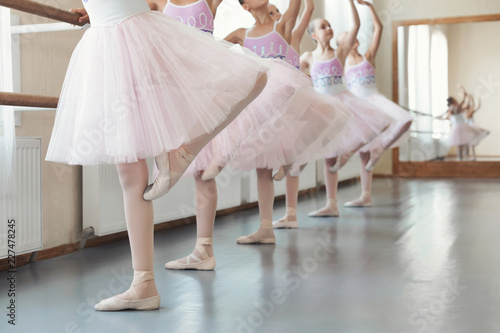 Girls training dance moves near ballet barre