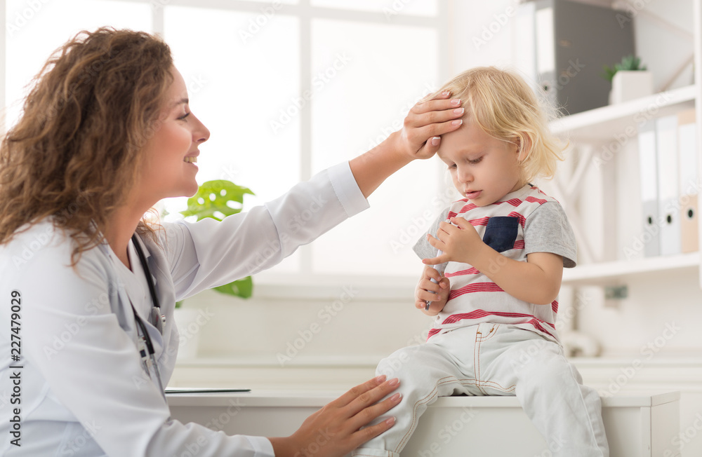 Fototapeta premium Doctor checking temperature of little boy, copy space