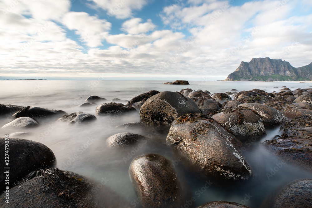 Long exposure of waves washing over rocks in Uttakleiv beach during day time. Lofoten, Norway.