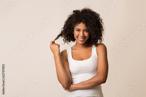 Smiling african-american woman flirting over light background