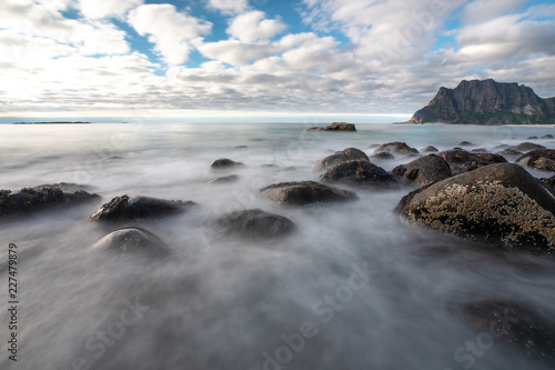 Long exposure of waves washing over rocks in Uttakleiv beach during day time. Lofoten, Norway. © Kertu