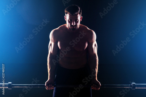 Muscular fitness man antique statue perfect muscles six pack abs and bare nude chest bodybuilder Apollo model bodybuilder makes exercise barbell for biceps in the gym on a black background