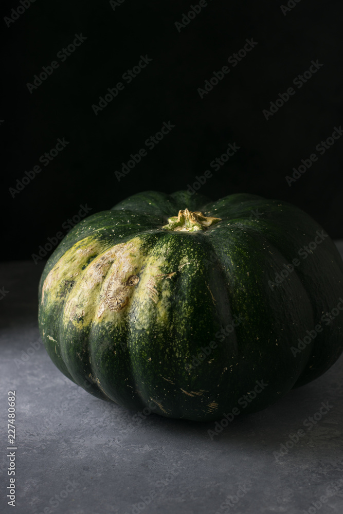 Big green pumpkin with yellow side on dark background Big green pumpkin with yellow side on dark background