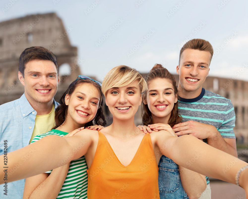 travel, tourism and vacation concept - group of happy smiling friends taking selfie over coliseum background