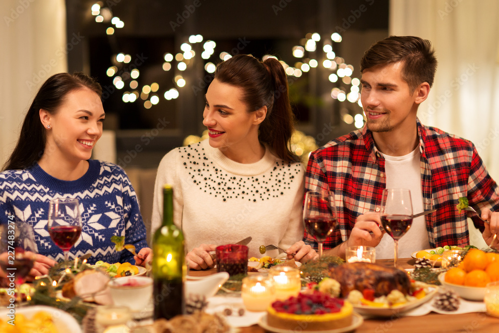 holidays and celebration concept - happy friends having christmas dinner at home and eating holidays and celebration concept - happy friends having christmas dinner at home and eating