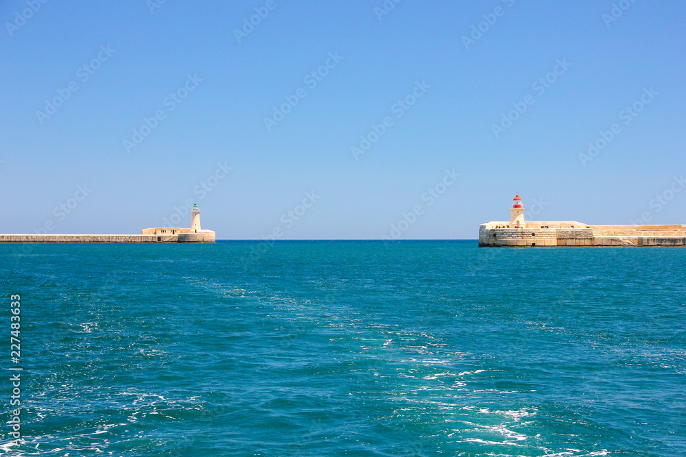 Yacht track on blue water with background of two lighthouses in bright sunny day