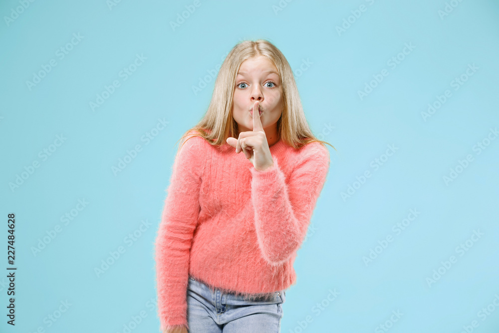 Secret, gossip concept. Young teen girl whispering a secret behind her hand isolated on trendy blue studio background. Young emotional girl. Human emotions, facial expression concept. Secret, gossip concept. Young teen girl whispering a secret behind her hand isolated on trendy blue studio background. Young emotional girl. Human emotions, facial expression concept.